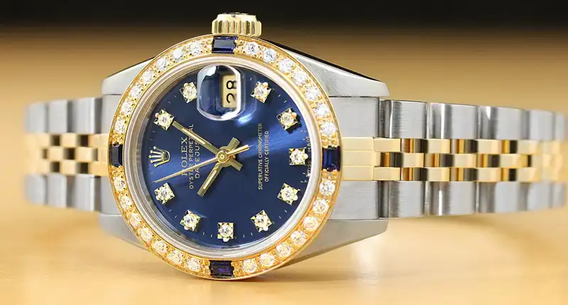 Rolex Datejust watch featuring a blue dial, diamond hour markers, and a two-tone metal bracelet.