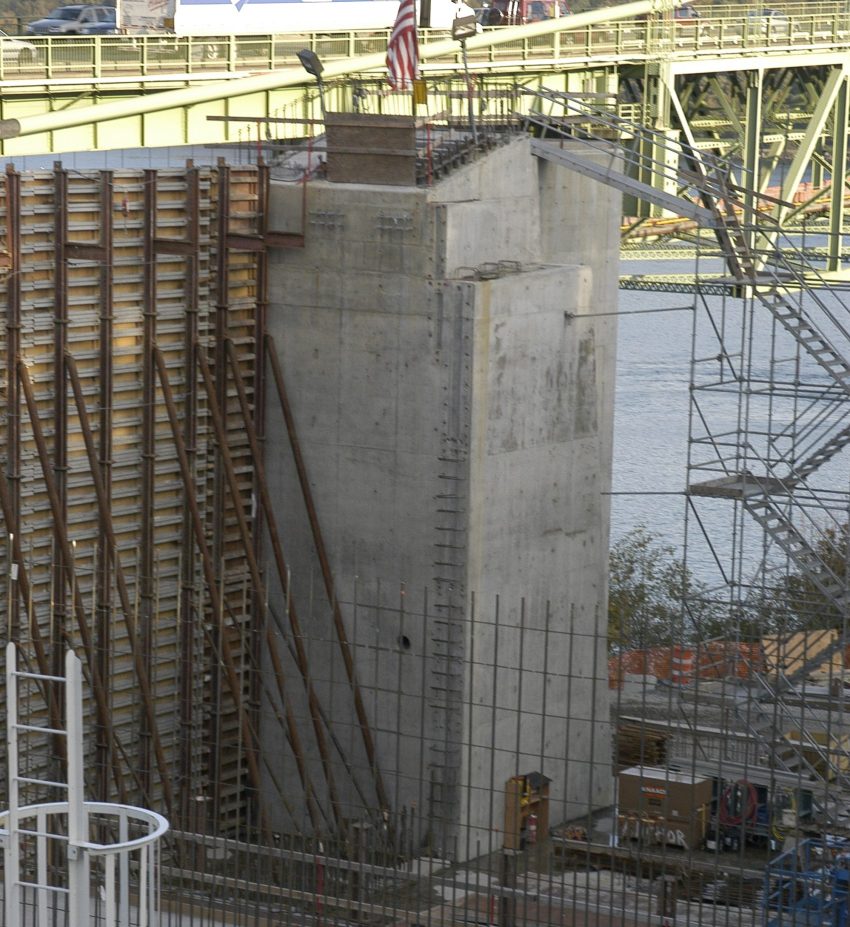 Concrete construction structure with rebar framework and an American flag on top.