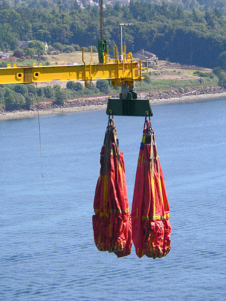 Red Safety Harnesses on Crane Hook Two red safety harnesses suspended from a crane hook over water, showcasing industrial lifting equipment.