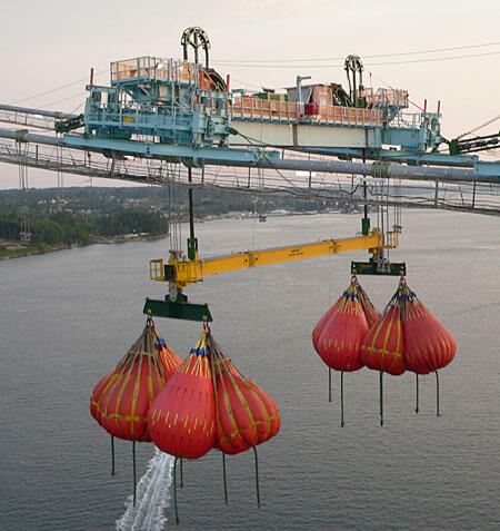 Aerial Water Transport System with Buckets Aerial water transport system featuring multiple red and yellow buckets suspended over water, showcasing industrial equipment in operation.