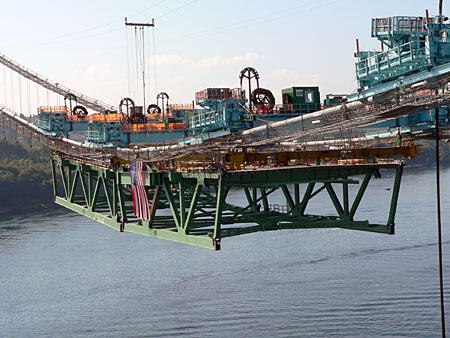 Suspension Bridge Construction Equipment Heavy construction equipment on a suspension bridge with containers, showcasing engineering and infrastructure development.