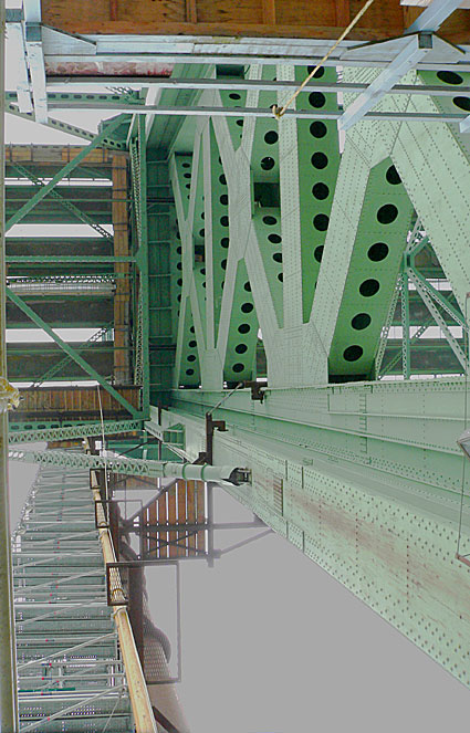 Detailed view of an industrial bridge structure showcasing green steel beams and rivets, highlighting engineering design and construction.