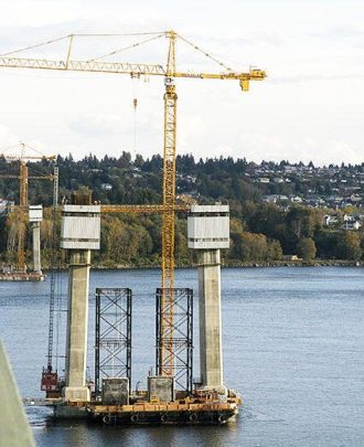 Bridge construction pillars with cranes and scaffolding over water, showcasing engineering and infrastructure development.