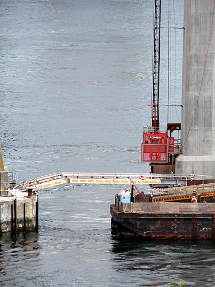 Construction dock featuring a crane and barge on water, with safety barriers visible. Ideal for marine construction projects.