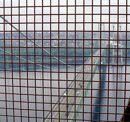 A view of a bridge seen through a grid, showcasing the structure and surrounding landscape in a unique perspective.