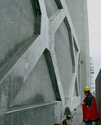 Concrete wall featuring geometric star patterns with a construction worker in a safety helmet and red jacket.