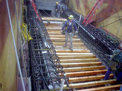 Construction workers on a building site with wooden beams and rebar in a concrete structure, showcasing active construction efforts.