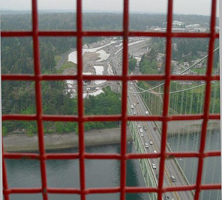 Aerial view of a bridge and roadway through a red grid, showcasing traffic and surrounding landscape.