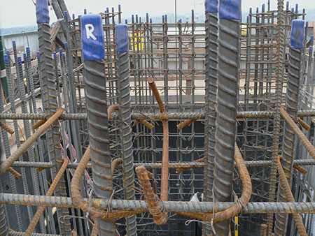 Close-up of a reinforced concrete structure with steel rebar and vertical rods at a construction site, showcasing construction materials and techniques.