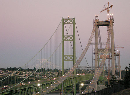 Tacoma Narrows Bridge Construction Tacoma Narrows Bridge under construction with green towers and cables, featuring Mount Rainier in the background.