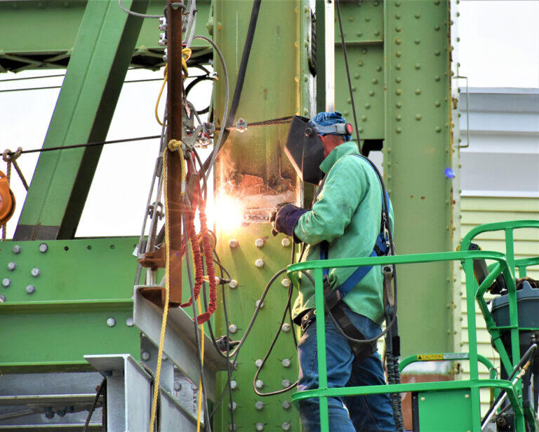 Welder Working on Metal Structure A welder in protective gear working on a metal structure with sparks flying in a construction setting.