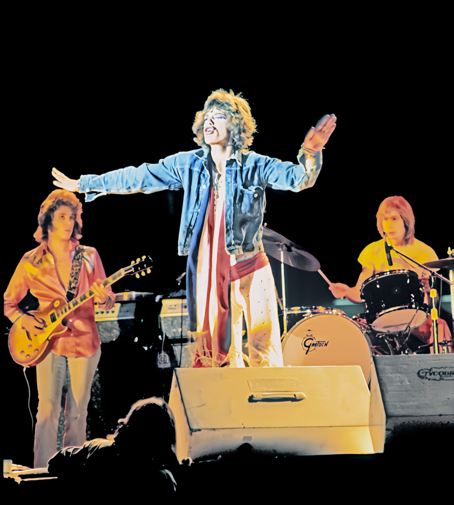 Rolling Stones performing live on stage with Mick Jagger in a denim jacket, Mick Taylor guitarist, and Charlie Watts drummer, showcasing vibrant energy.