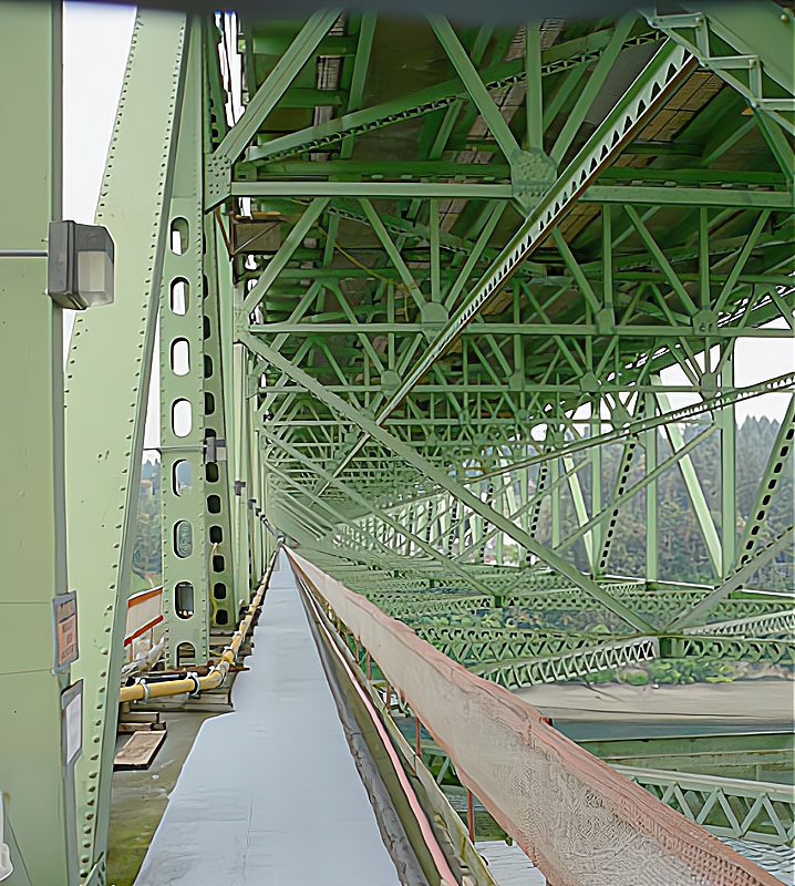 Interior view of a green steel bridge showcasing its structural framework and supports.