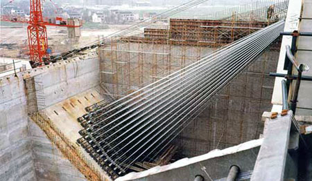 Construction site featuring steel cables and concrete structure, showcasing the framework and materials used in modern suspension bridge projects.