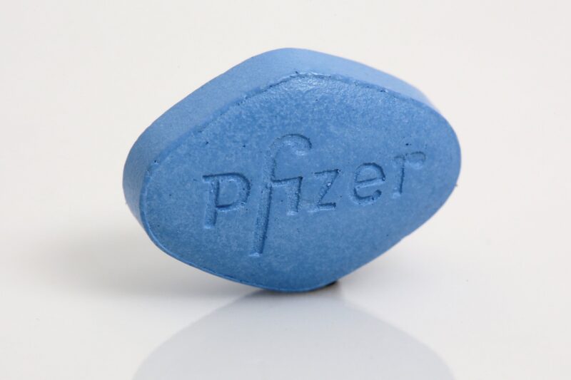 A blue oval-shaped tablet with the Pfizer logo imprinted on one side.